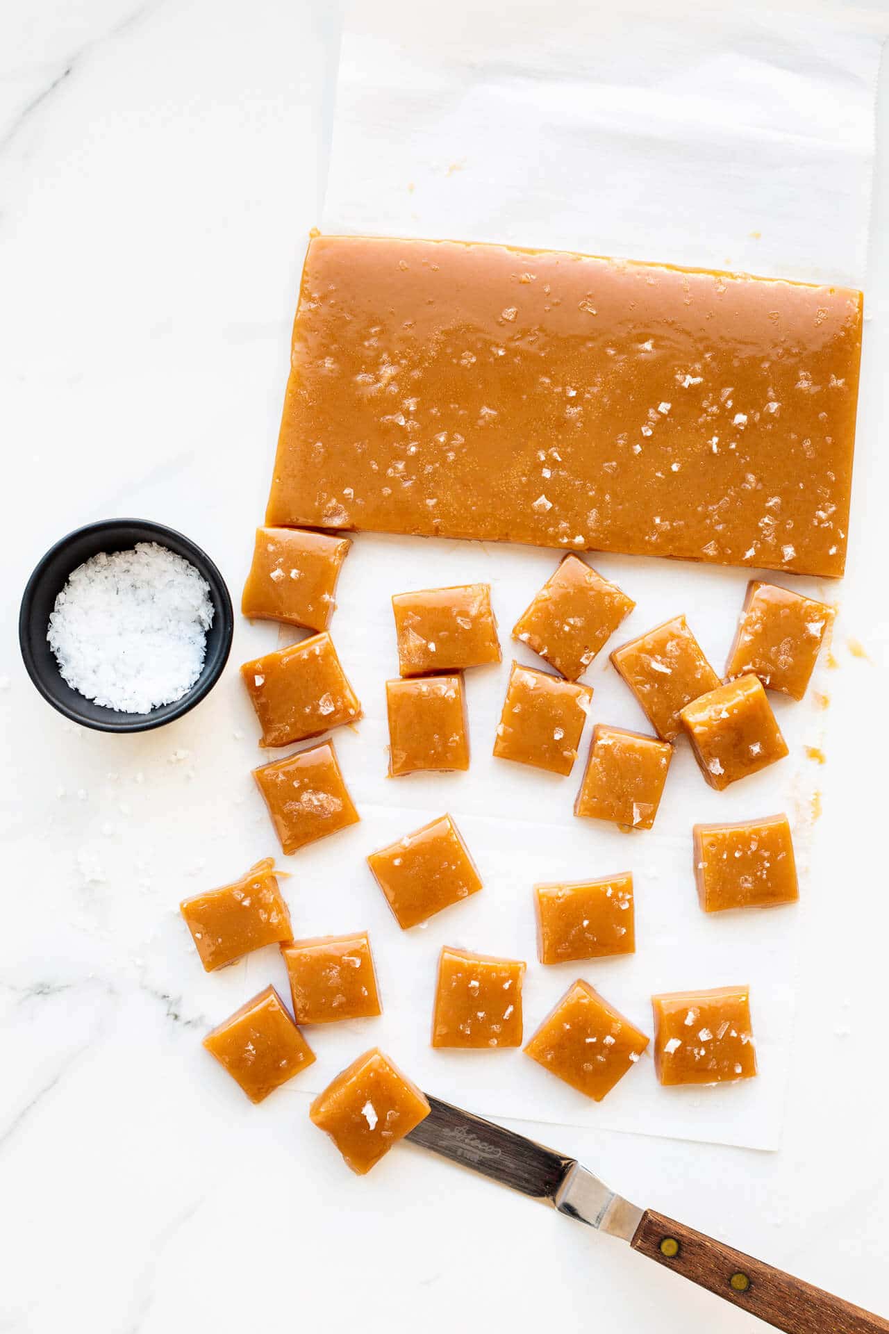 Cutting salted caramels into squares, garnishing with flaky sea salt