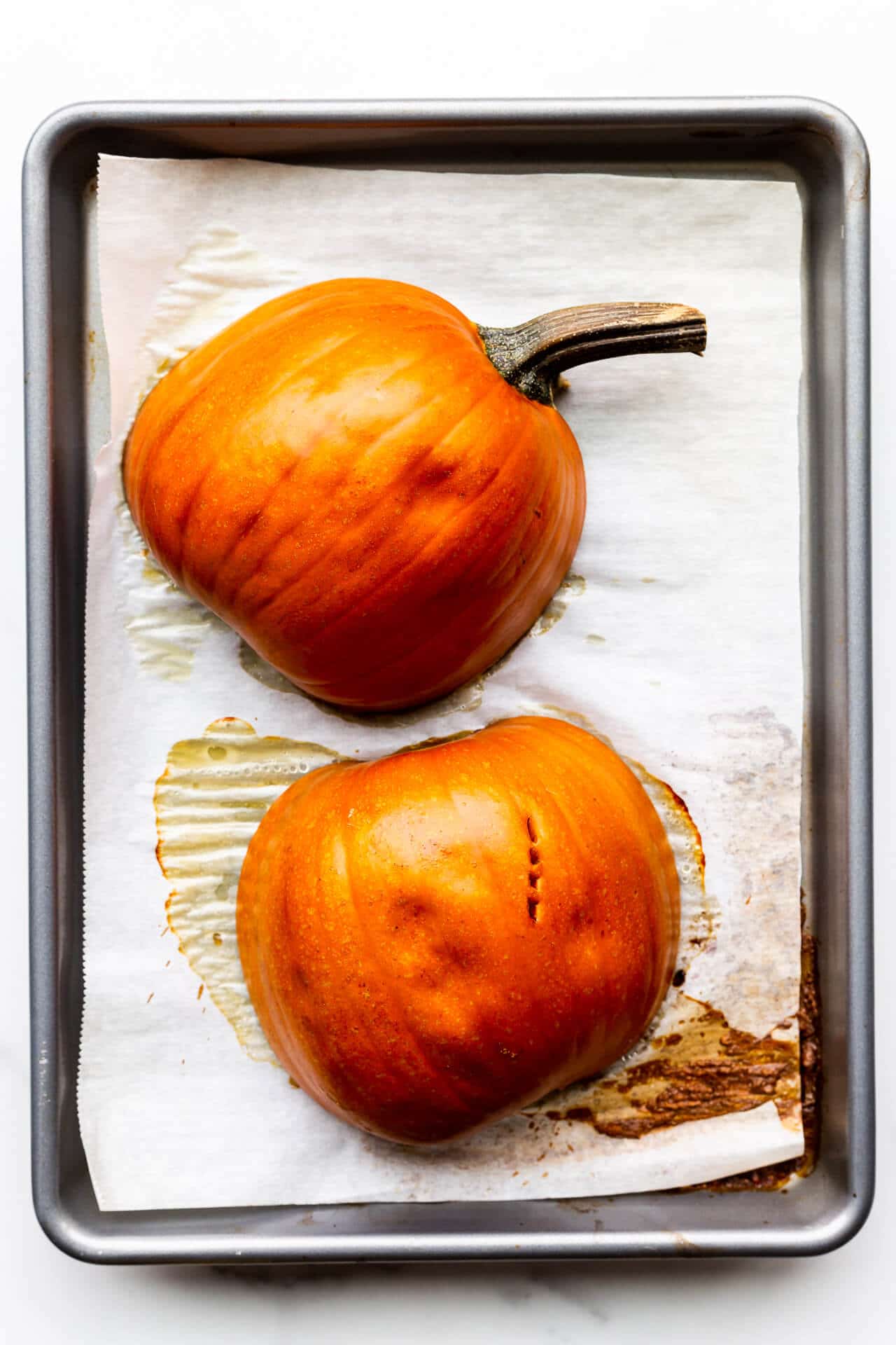 Sugar pie pumpkin cut in half and roasted cut side down on a parchment-lined baking sheet.