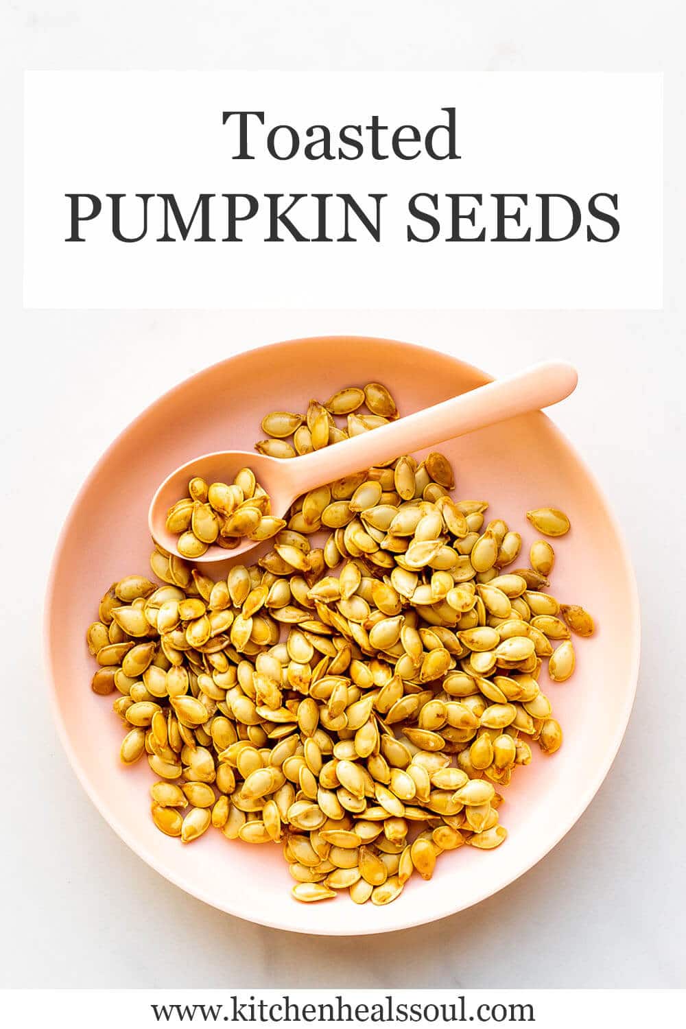 Roasted pumpkin seeds in a pink bowl with a pink spoon for serving