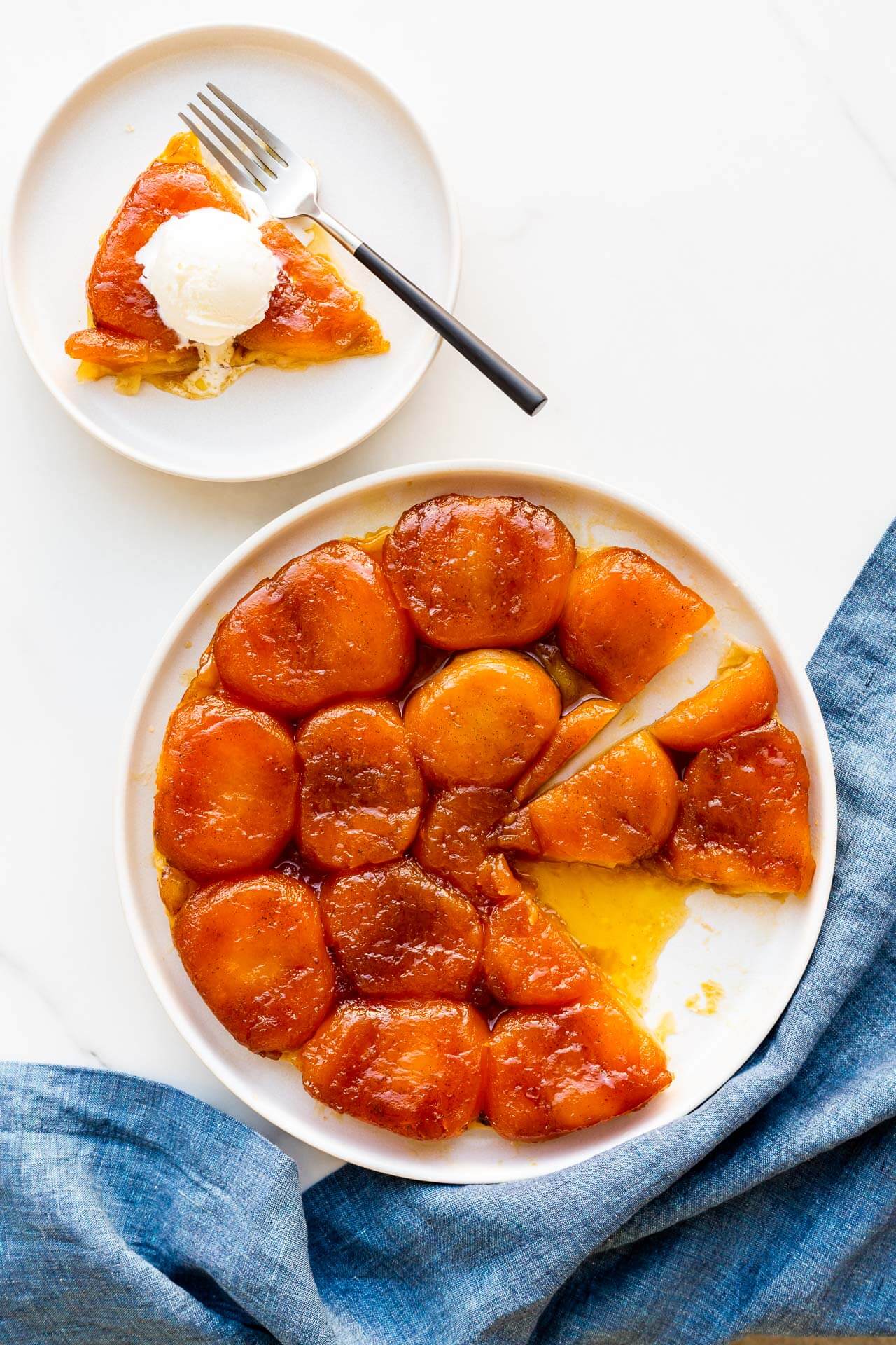 Serving a slice of apple tarte tatin on a plate with a scoop of ice cream.