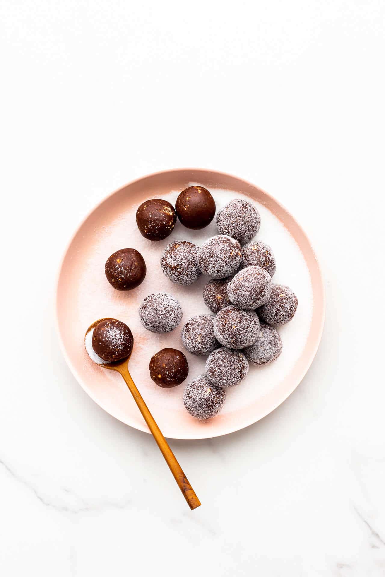 Coating amaretto balls in granulated sugar.