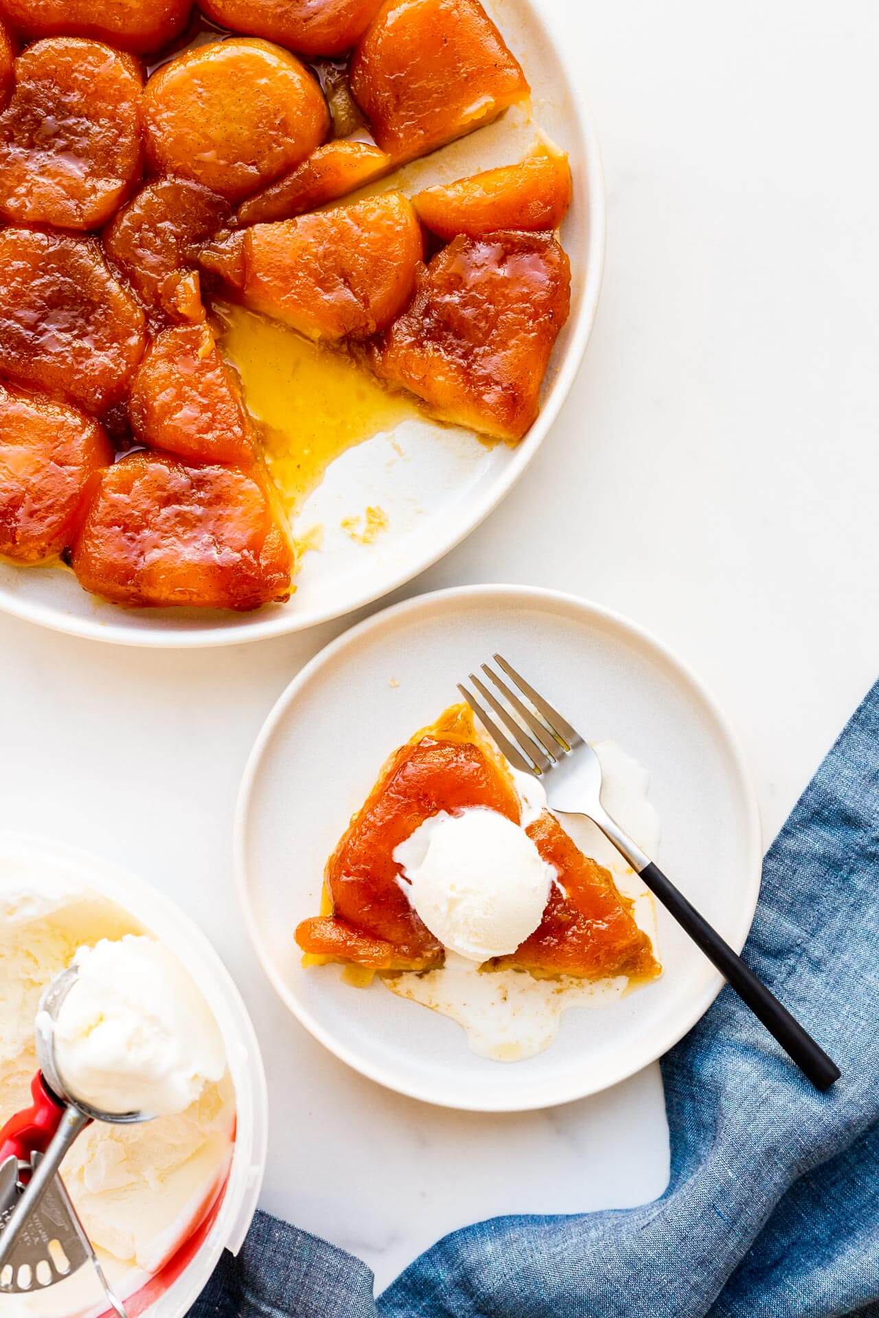 Sliced apple tarte tatin served à la mode with vanilla ice cream.