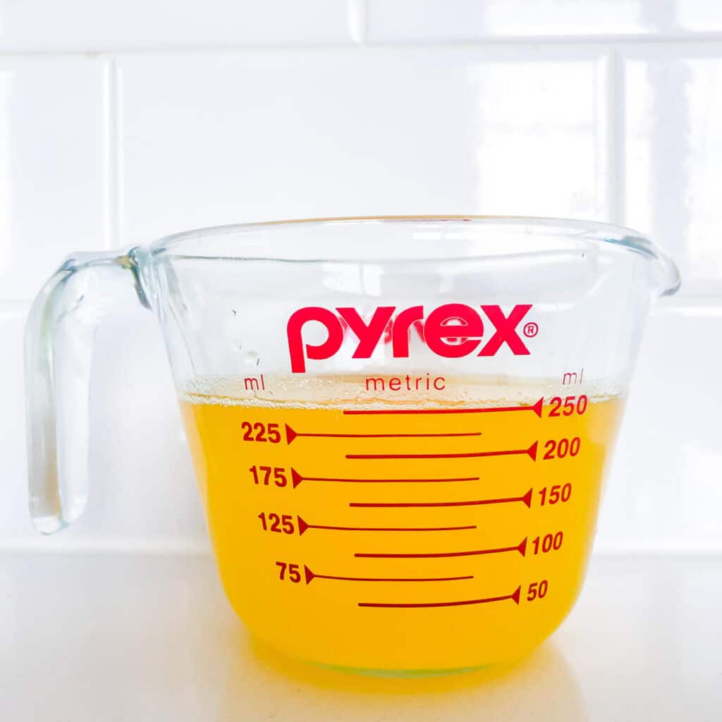 Warm clarified butter in a measuring cup is golden in colour and fluid