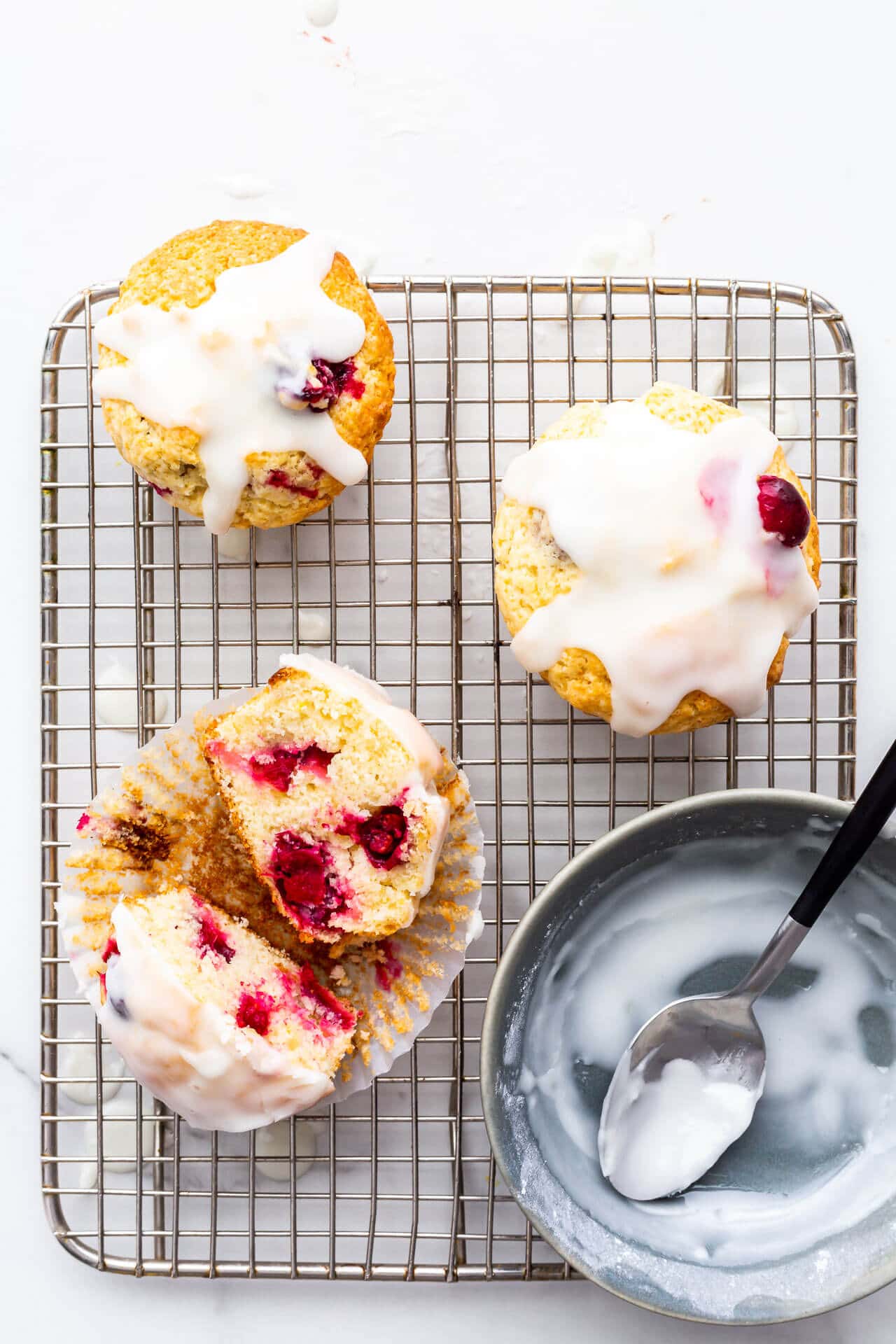 Glazed cranberry lemon muffins on a cooling rack.