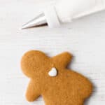 Decorating a gingerbread cookie with royal icing using a piping bag and a fine tip.