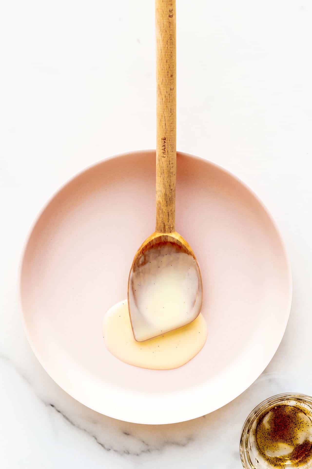 A plate with a wooden spoon with thick custard sauce.