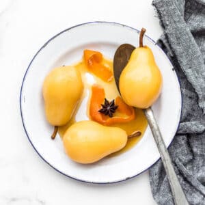 Poached pears on an enamelware plate.