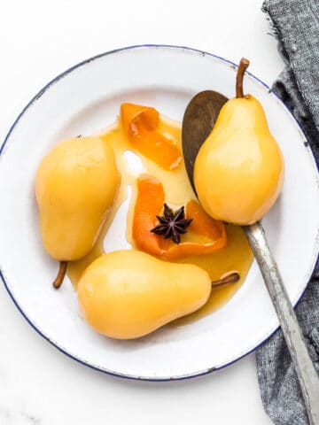 Poached pears on an enamelware plate.