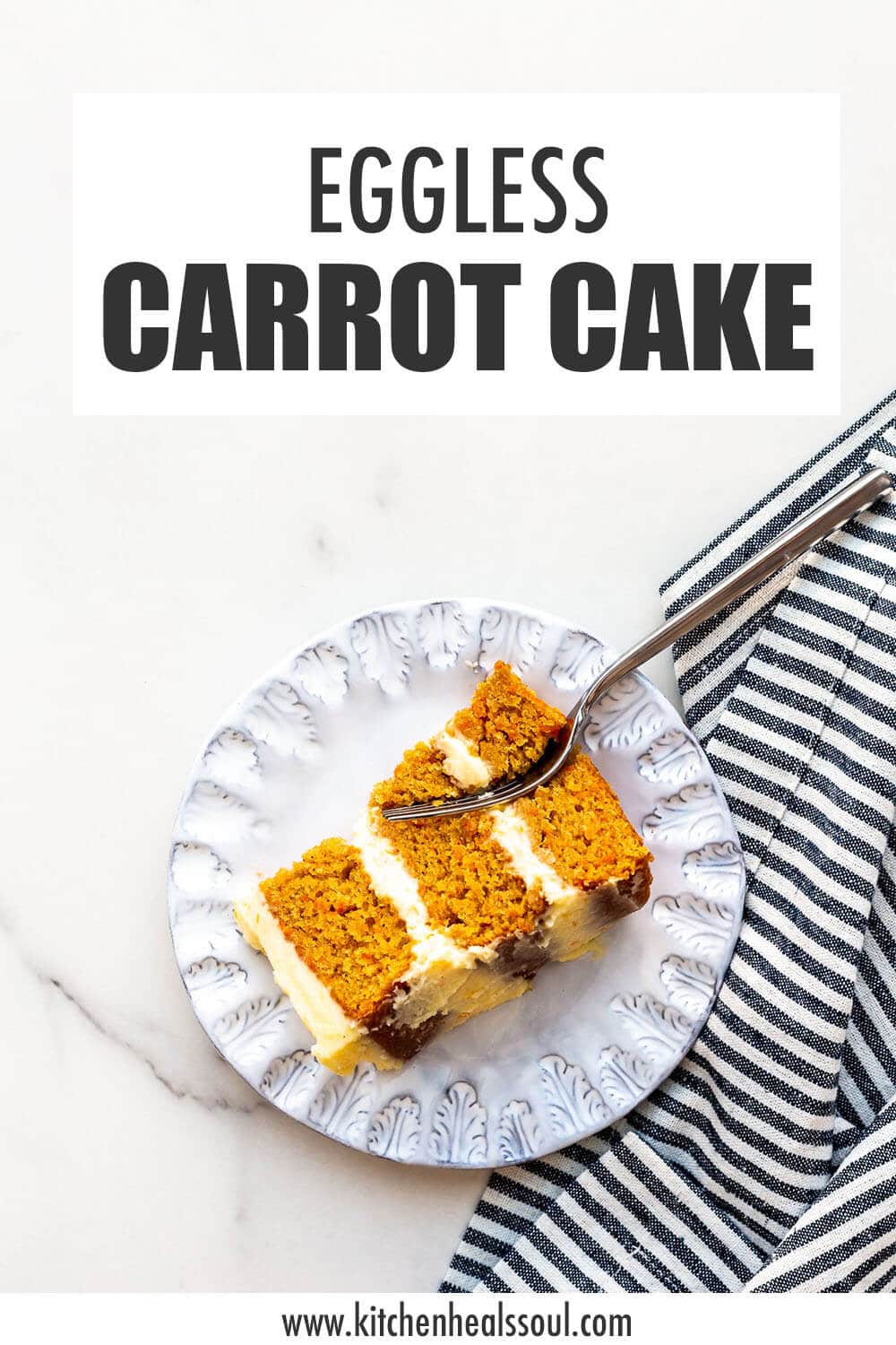 Slice of carrot cake on a blue plate with striped napkin and fork.