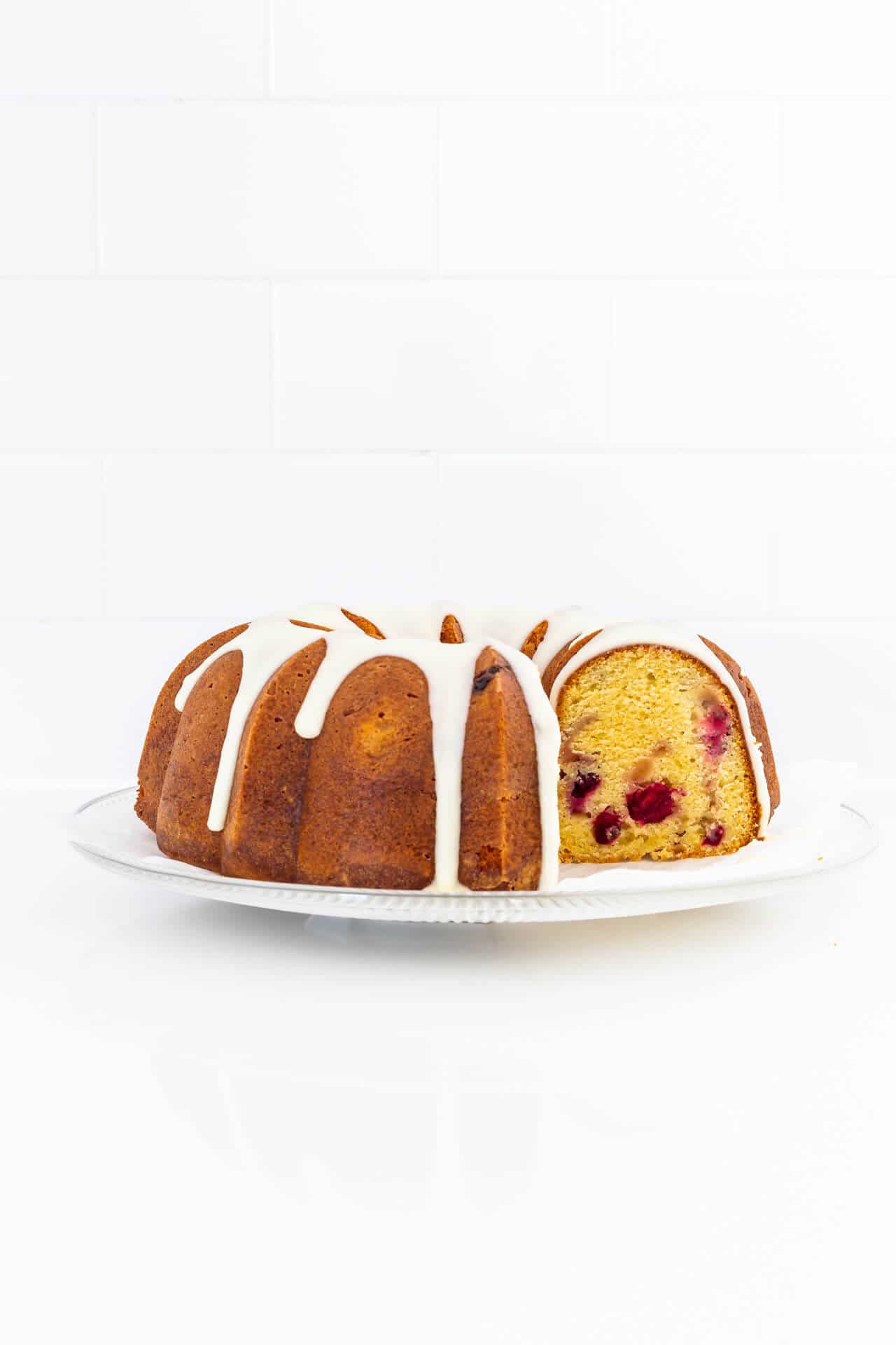 Glazed orange cranberry bundt cake on a plate.