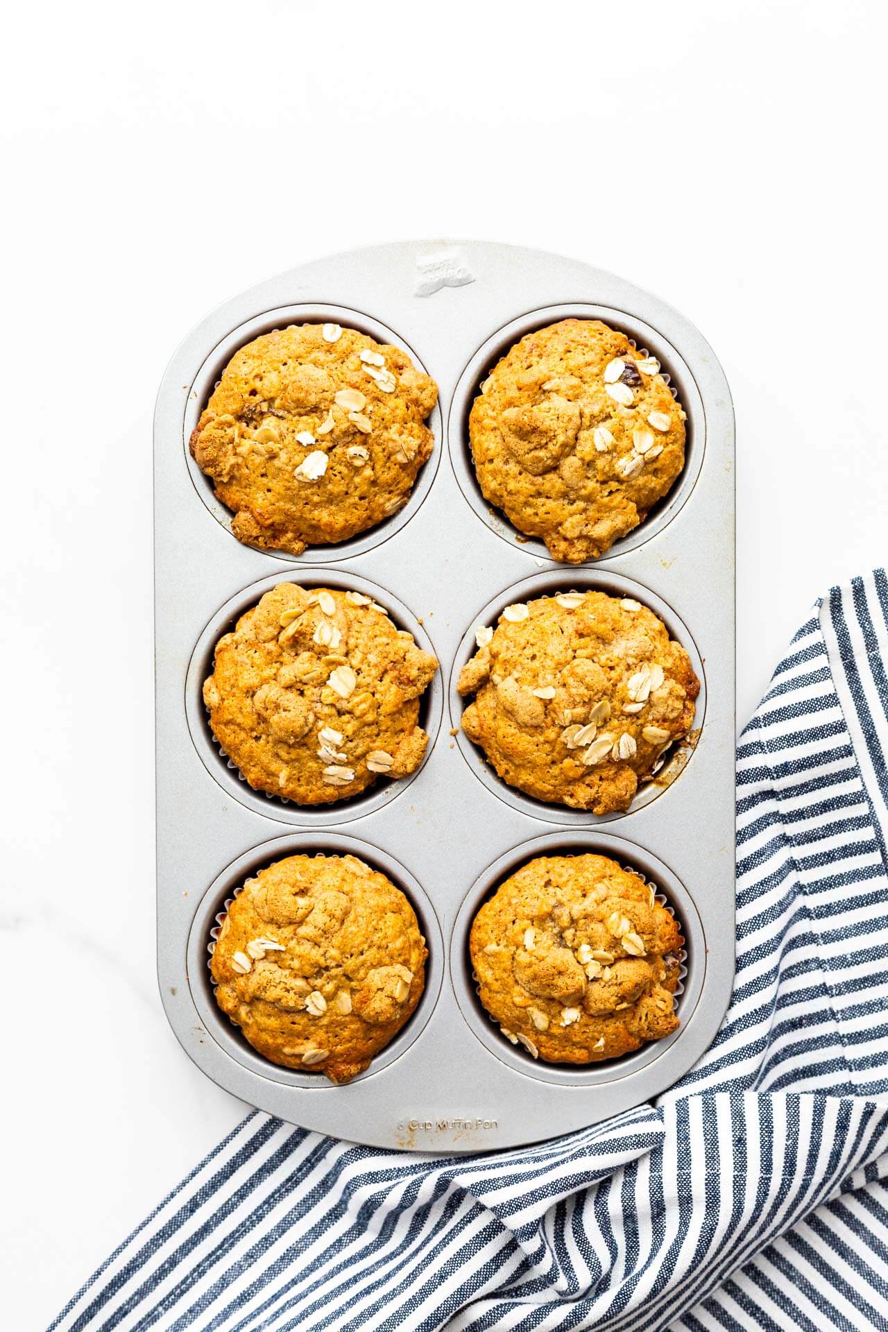 Freshly baked banana muffins with oats still in the muffin pan.