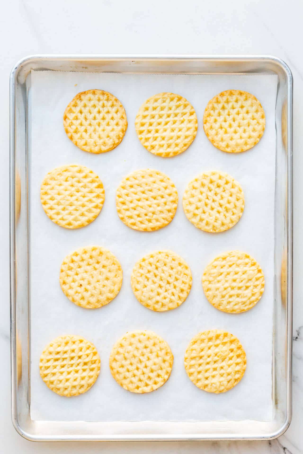 Freshly baked lemon shortbread on a parchment lined sheet pan.