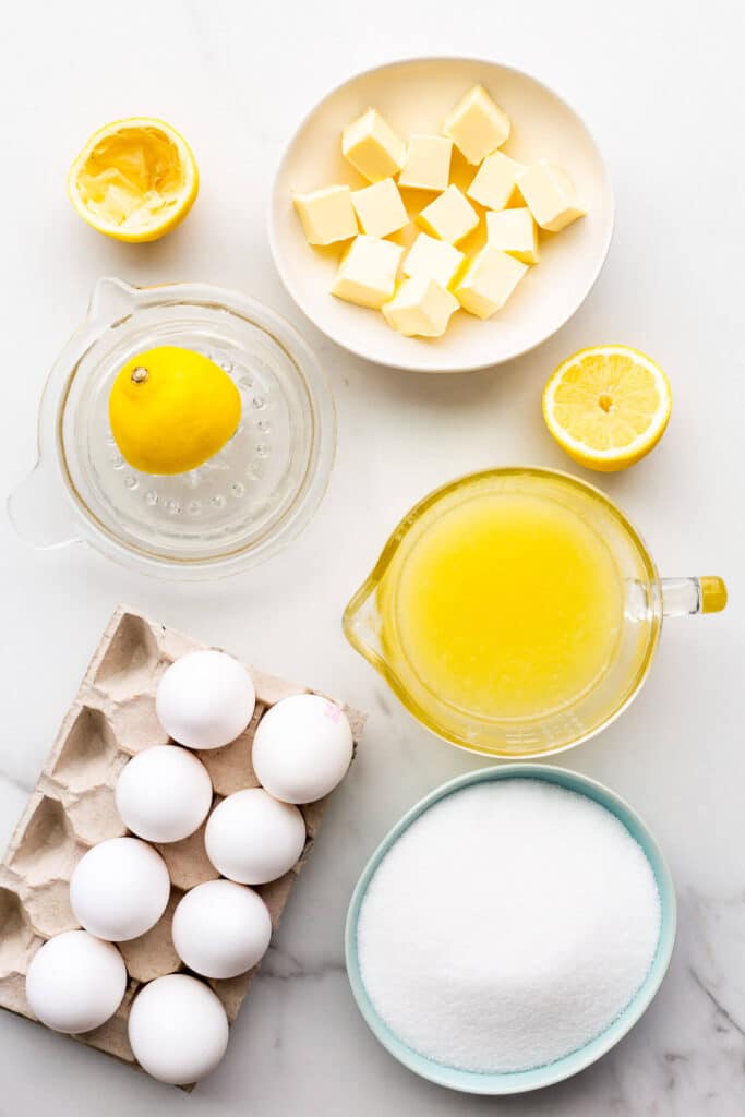 Ingredients for lemon curd measured out, including butter, lemon juice, sugar, and eggs.