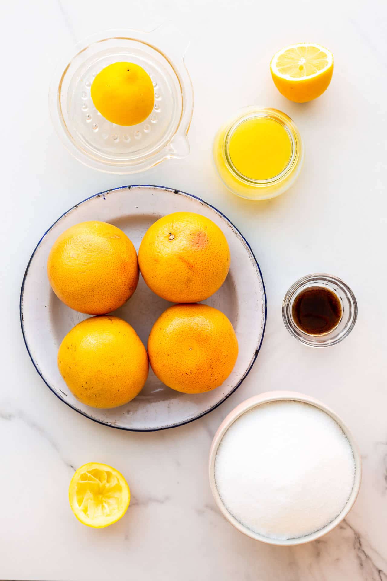 Ingredients to make homemade grapefruit marmalade from scratch, including whole pink grapefruit, lemon juice, sugar, and vanilla bean paste.