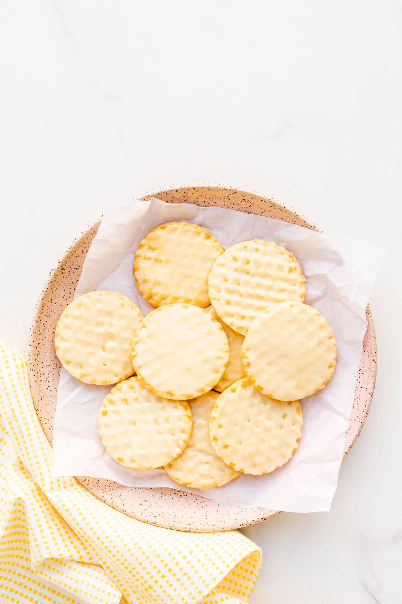A pink ceramic plate with glazed lemon shortbread cookies.