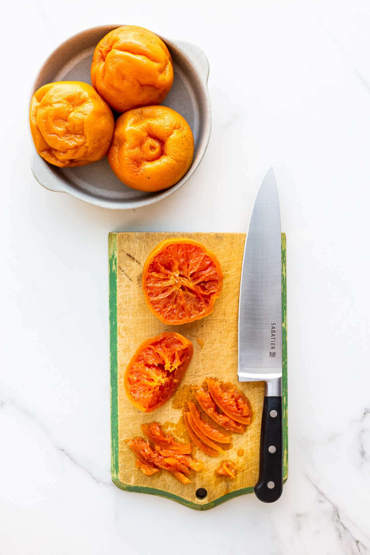 Slicing boiled grapefruit on a cutting board with a chef's knife to make marmalade.