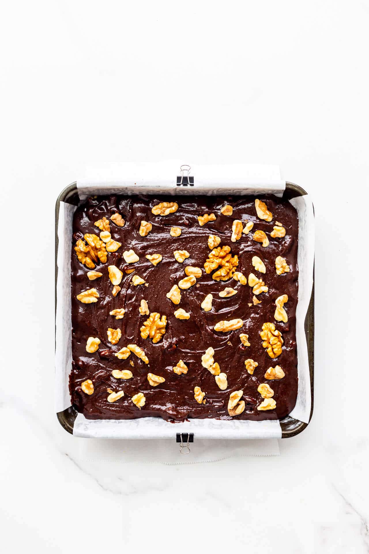 A square pan of batter for brownies with walnuts ready to be baked.