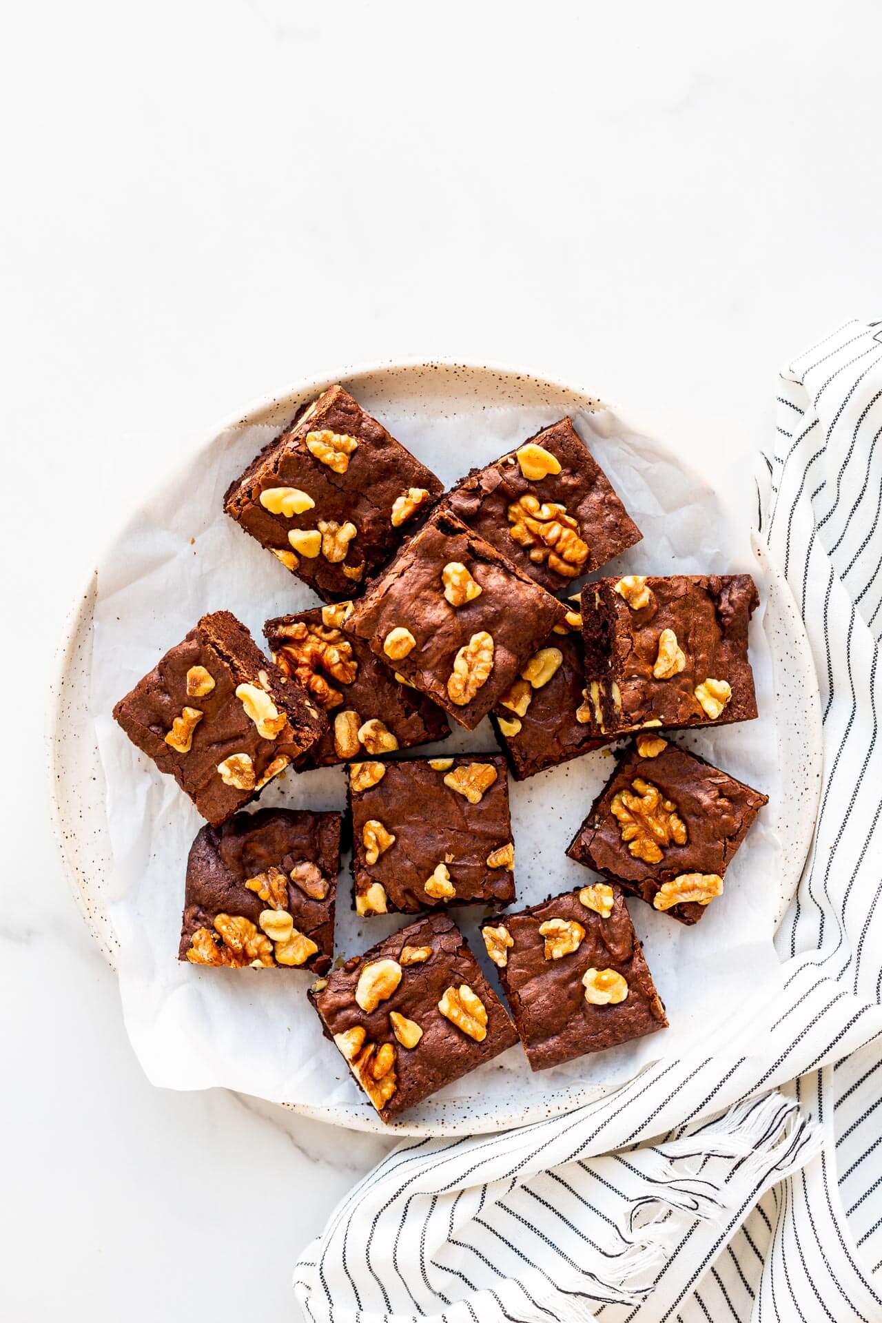 A plate of brownies with walnuts.