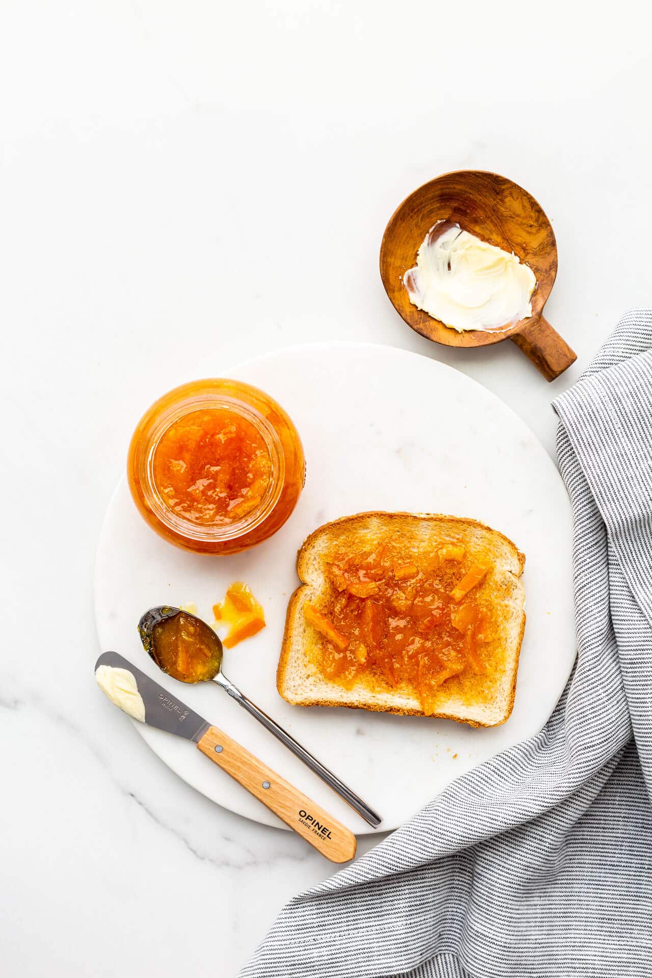 Slice of toast, buttered, and topped with orange marmalade.