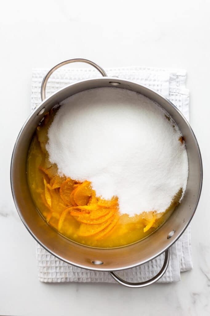 A pot of sliced oranges and sugar, ready to be boiled to make homemade orange marmalade.