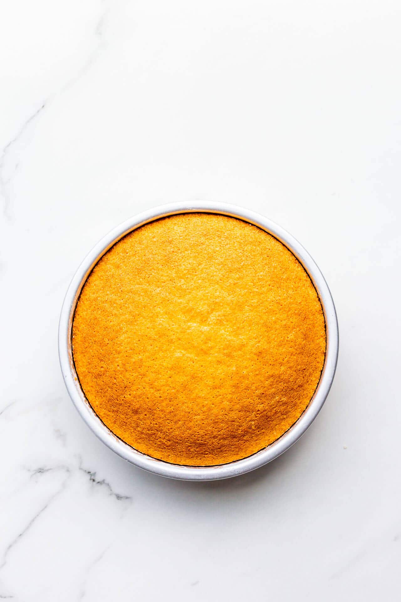 Freshly baked hot milk sponge cake cooling in cake pan.