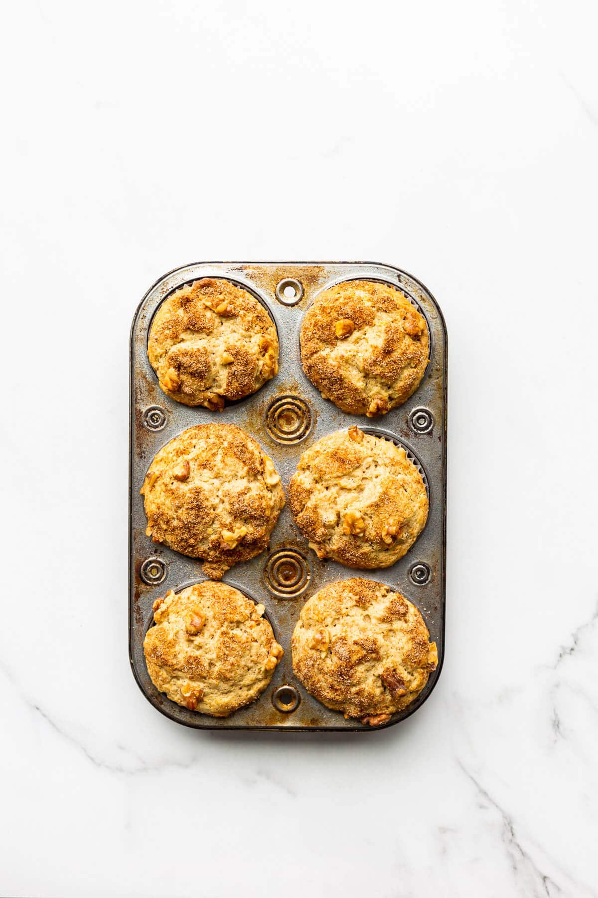 A muffin pan of carrot muffins, freshly baked and cooling.