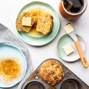 Freshly baked carrot muffins being served on plates with butter.