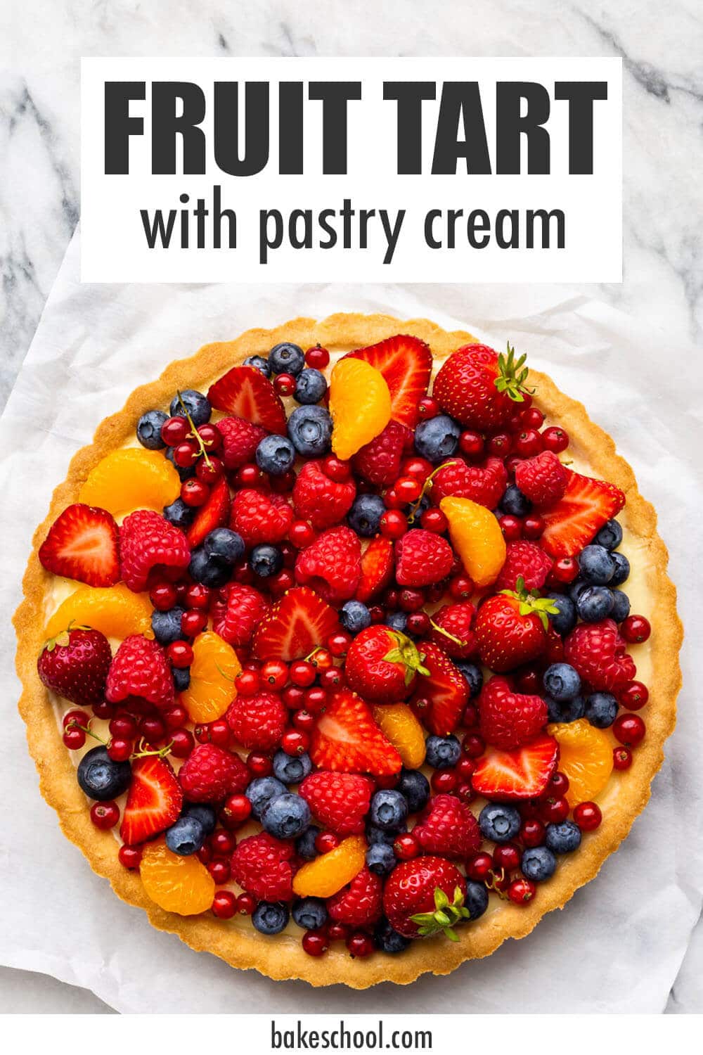 Fruit tart with vanilla pastry cream on parchment paper on marble.