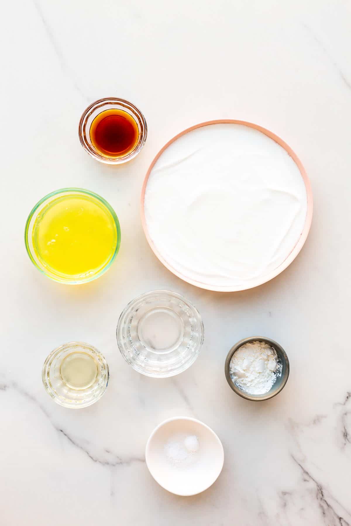 Ingredients measured out to make a pavlova from scratch from egg whites, super fine sugar, cream of tartar, cornstarch, vinegar, vanilla, and salt.