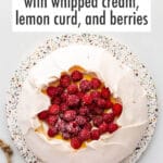Pavlova cake filled with whipped cream, lemon curd, and raspberries.