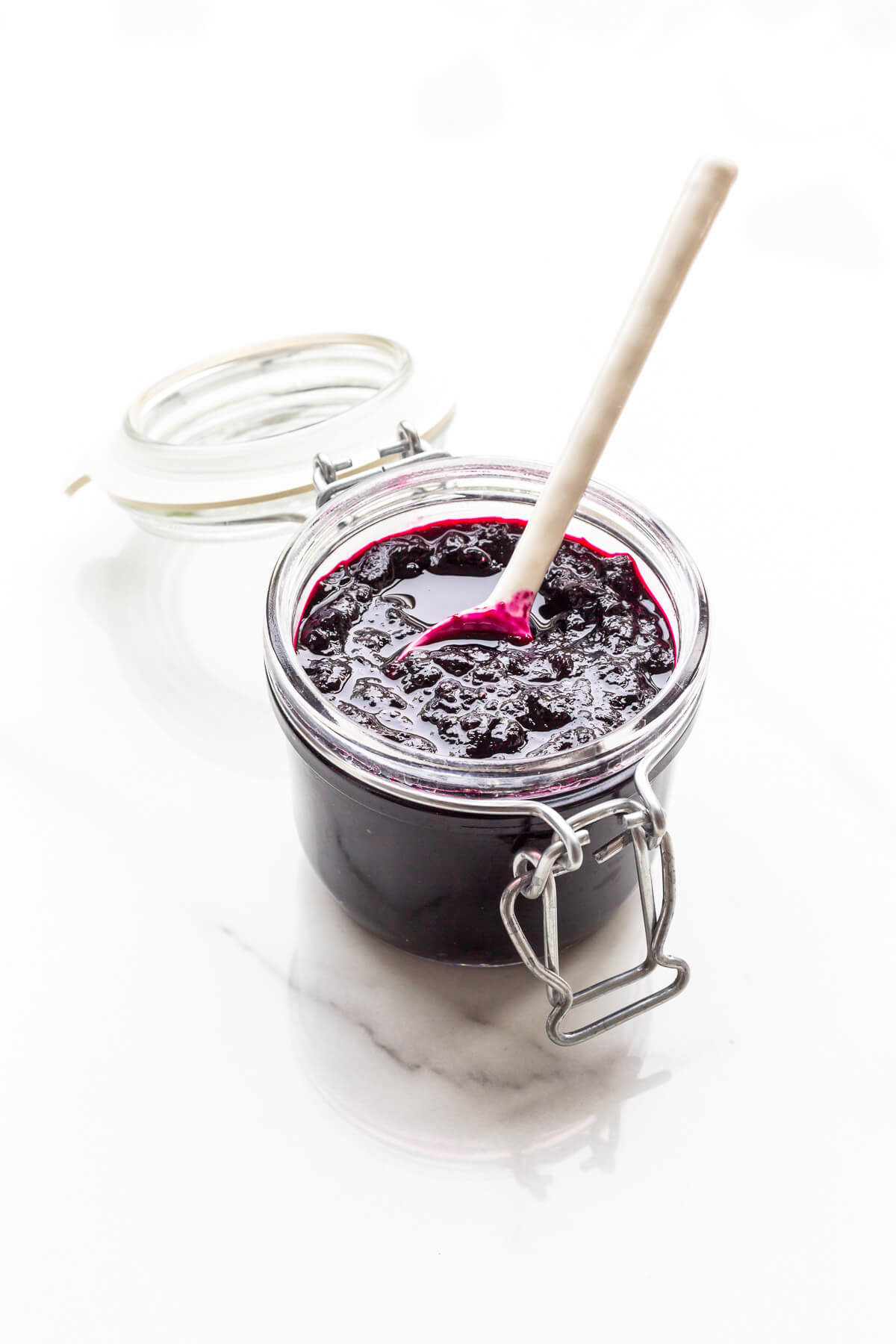 A jar of homemade blueberry jam with a spoon.