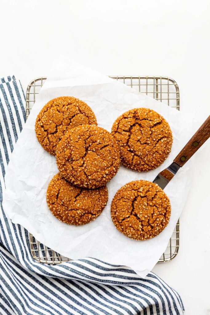 Freshly baked molasses cookies coated in turbinado sugar cooling down on a wire rack.