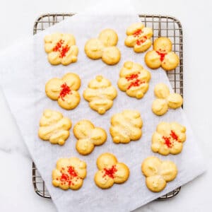 Spritz cookies topped with colourful sprinkles on a cooling rack.