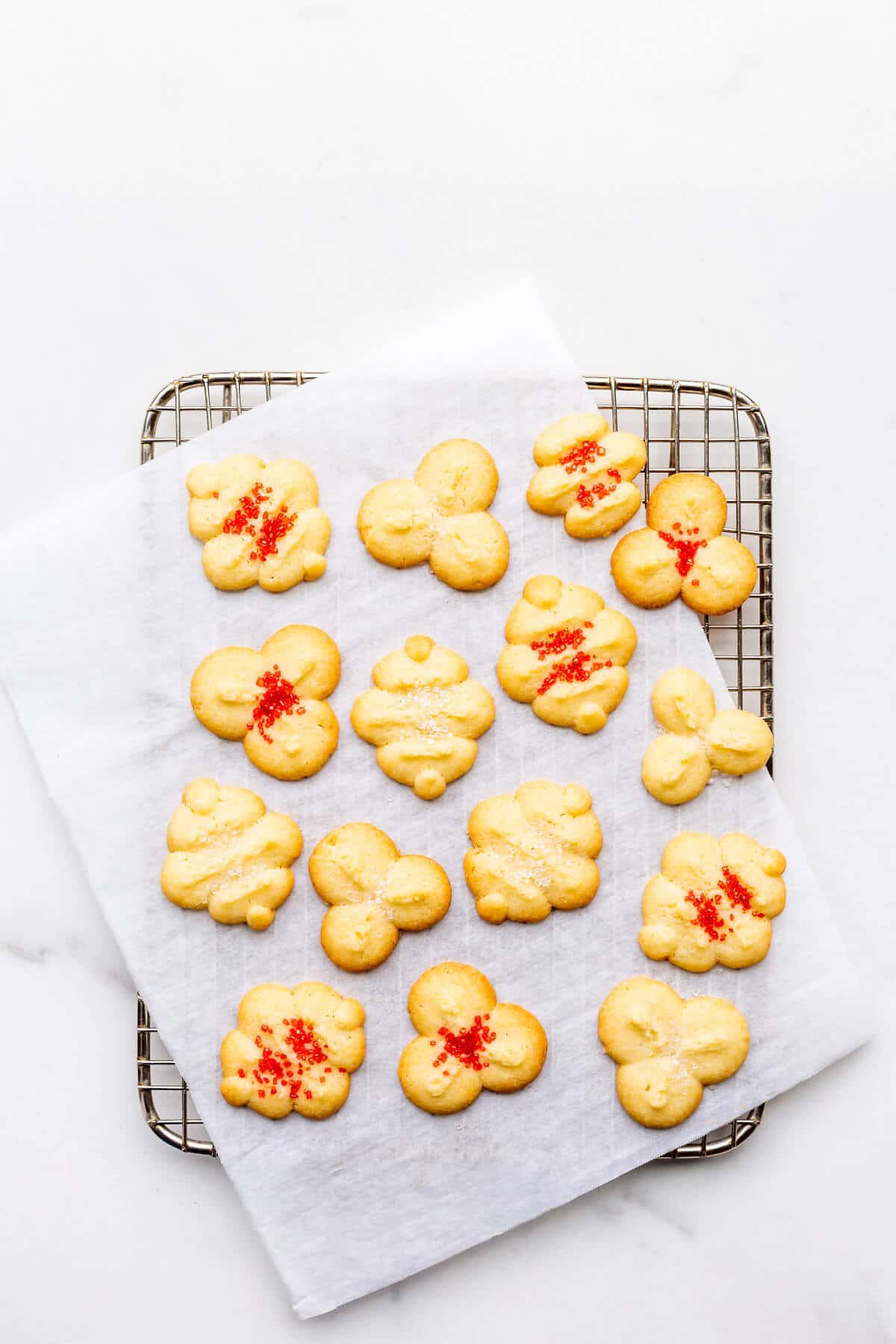 Spritz cookies topped with colourful sprinkles on a cooling rack.