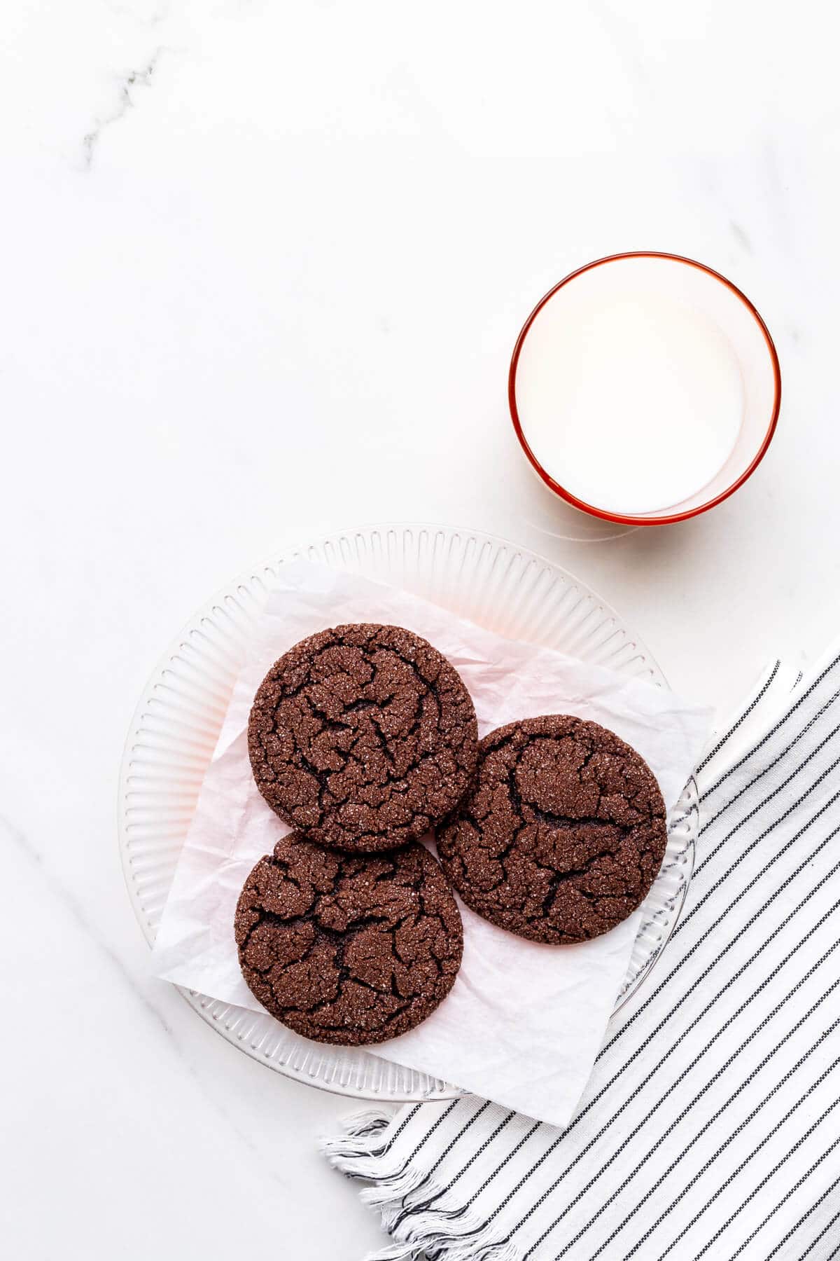 A plate of chocolate sugar cookies and a glass of milk.