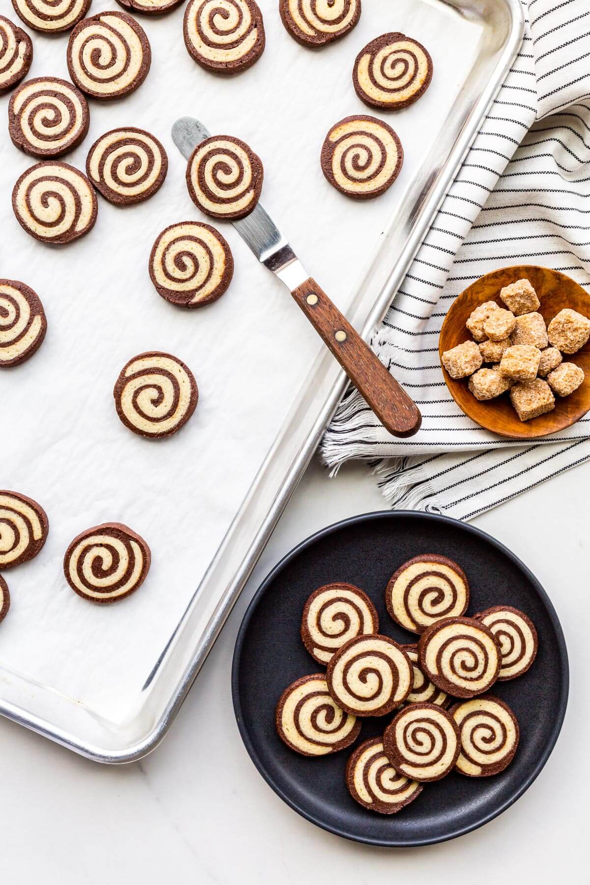 Transferring pinwheel cookies from a sheet pan to a plate to serve them.