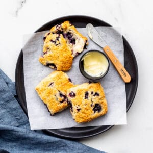 A plate of blueberry scones served with butter.