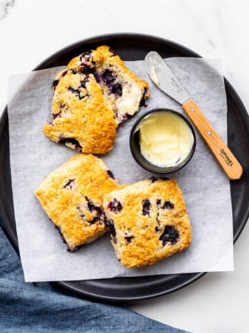 A plate of blueberry scones served with butter.