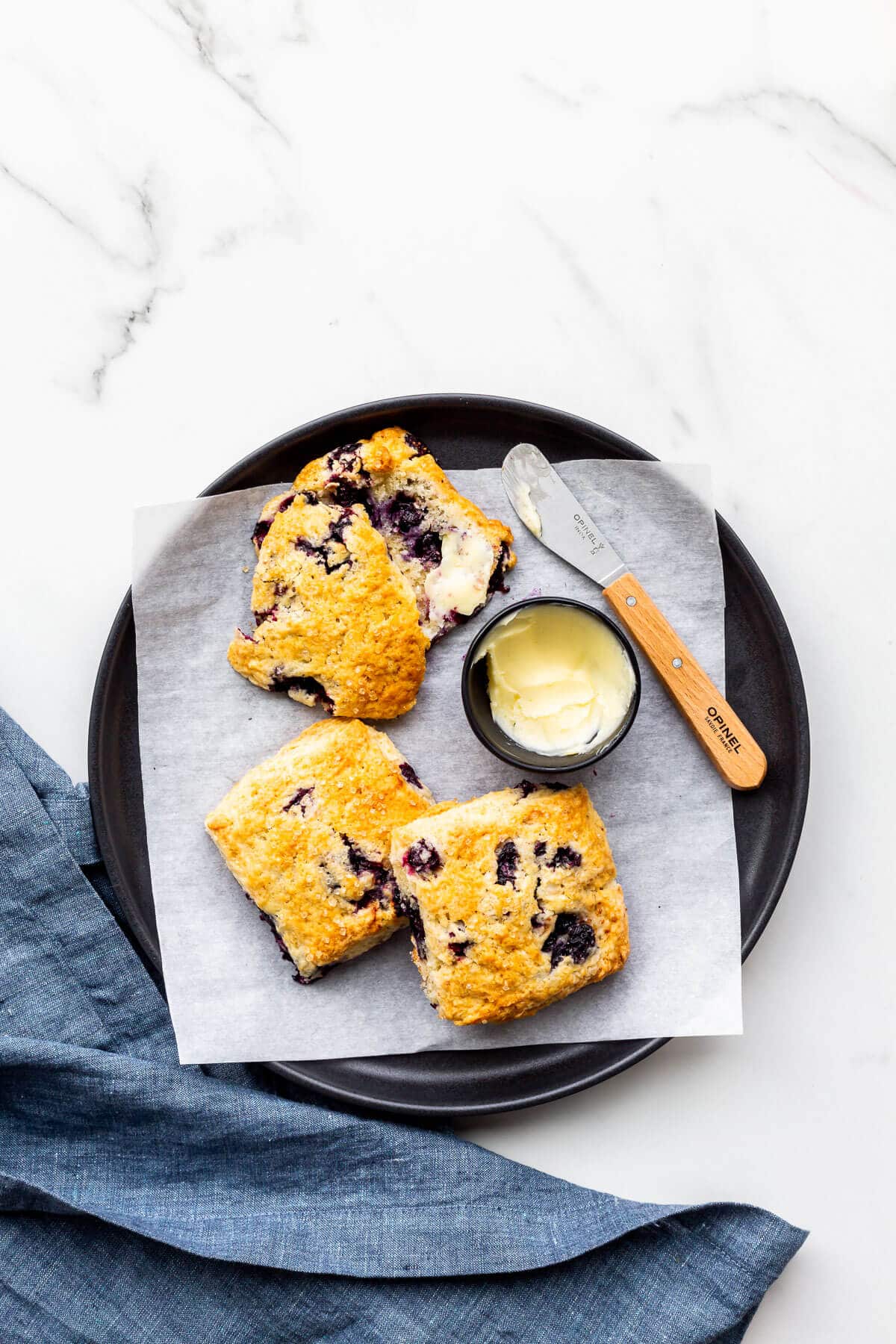 A plate of blueberry scones served with butter.