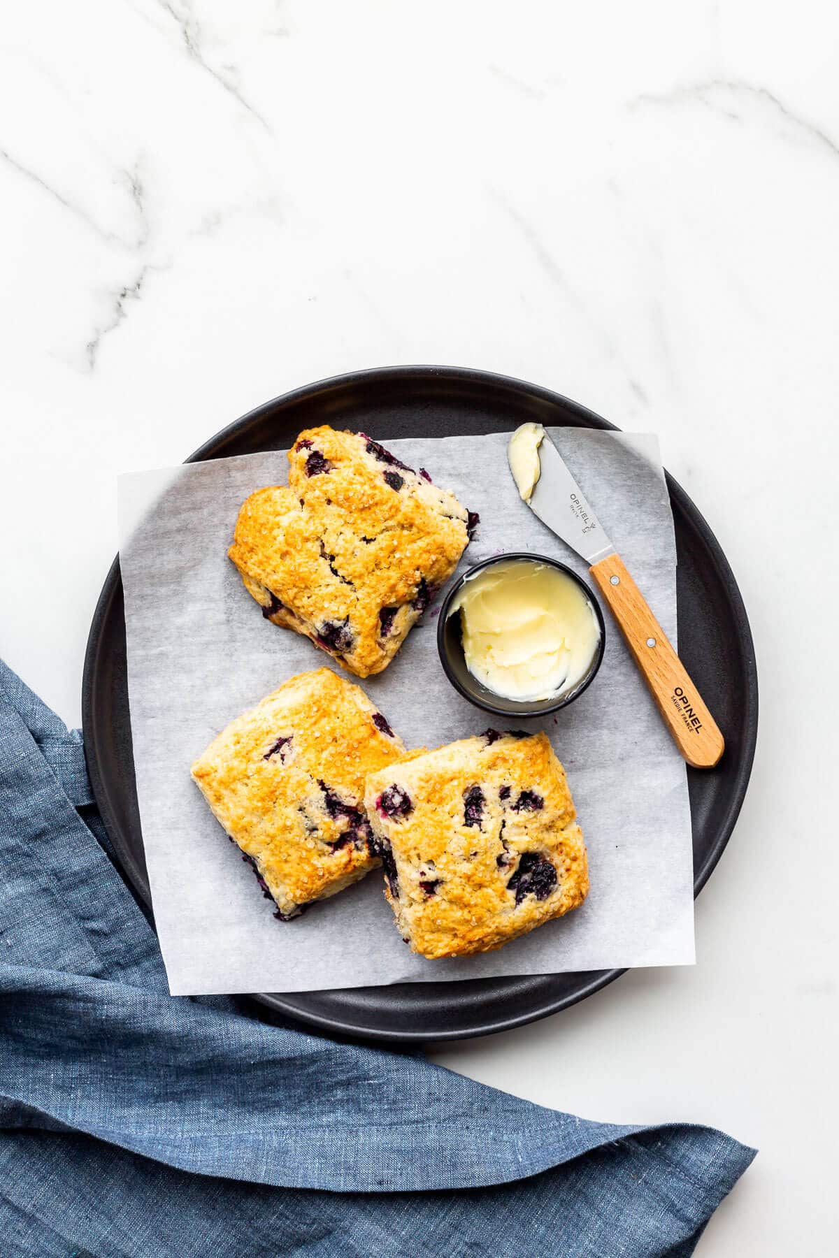 A plate of blueberry scones served with butter.