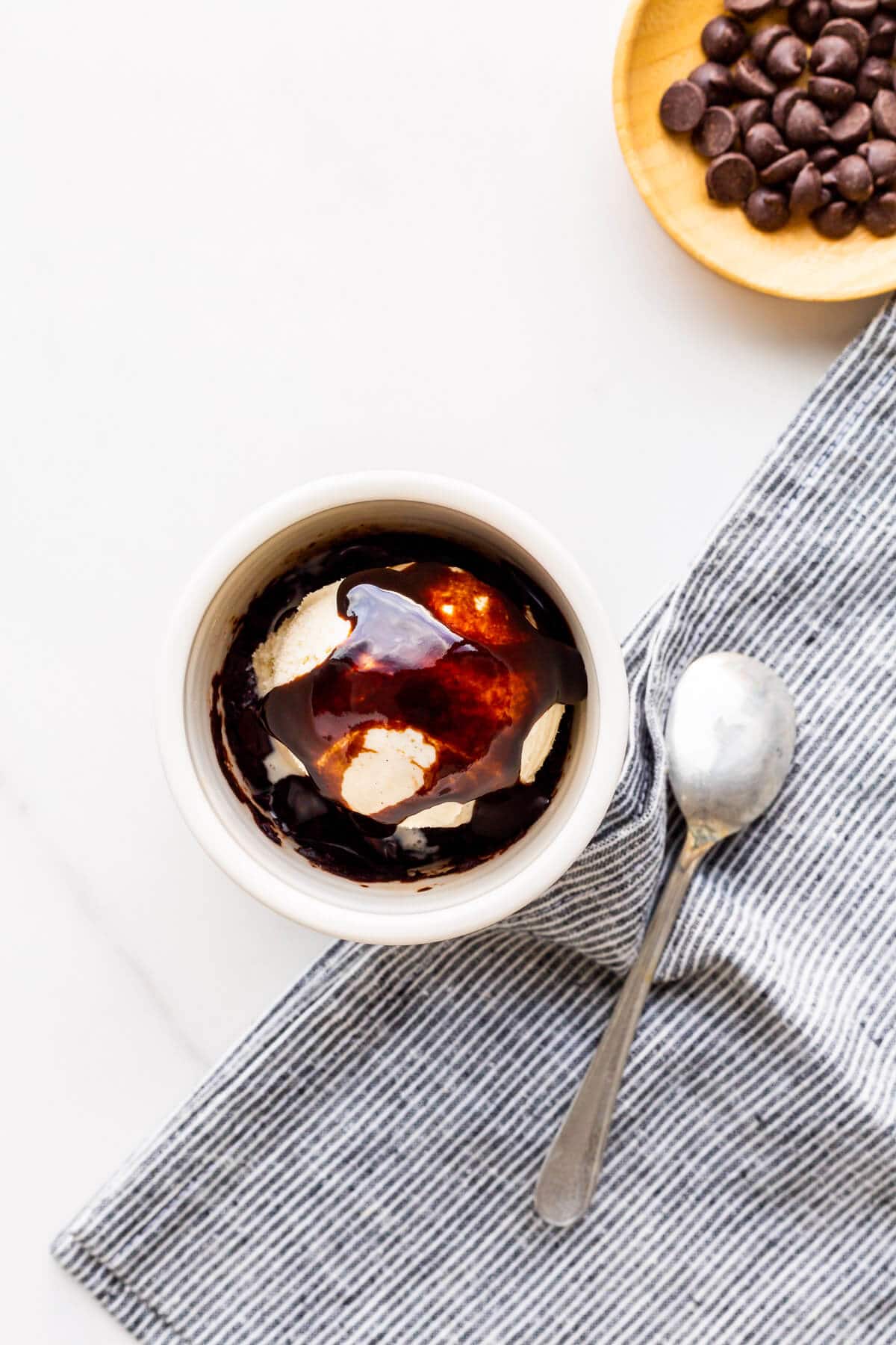 Chocolate mug cake topped with ice cream and chocolate syrup.