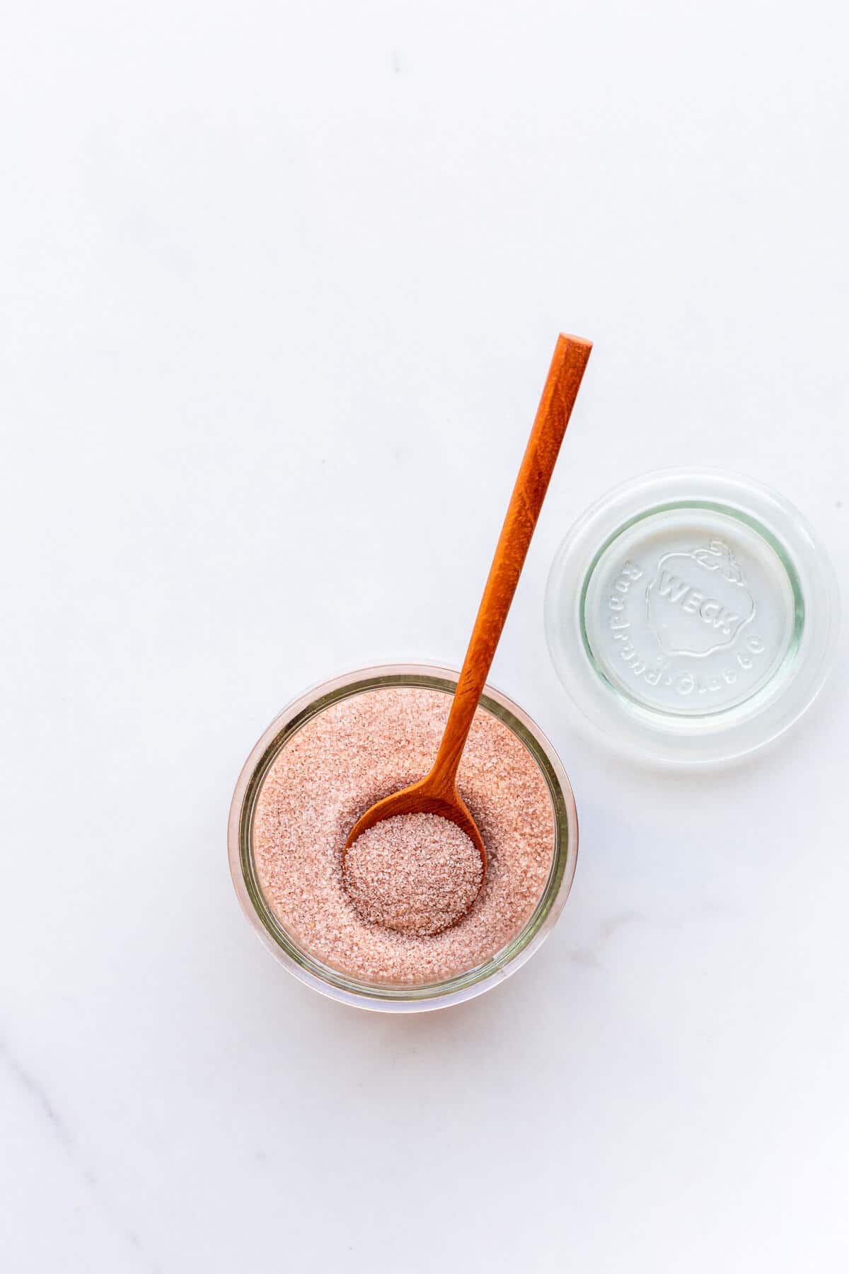 An open jar of cinnamon sugar with a wooden spoon.