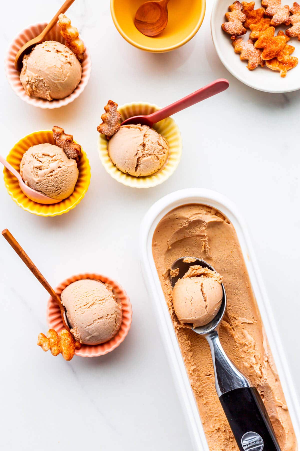 Homemade pumpkin ice cream scooped into little bowls and served with pie crust cookies.