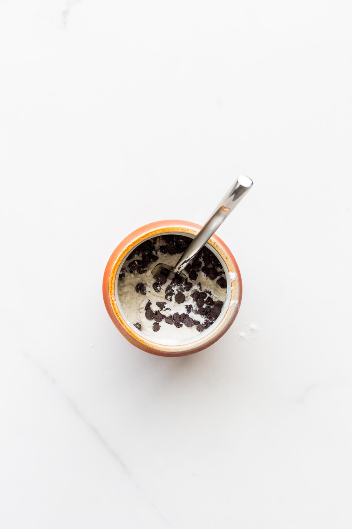 Mixing dry ingredients in a mug to make a chocolate chip mug cake in the microwave.