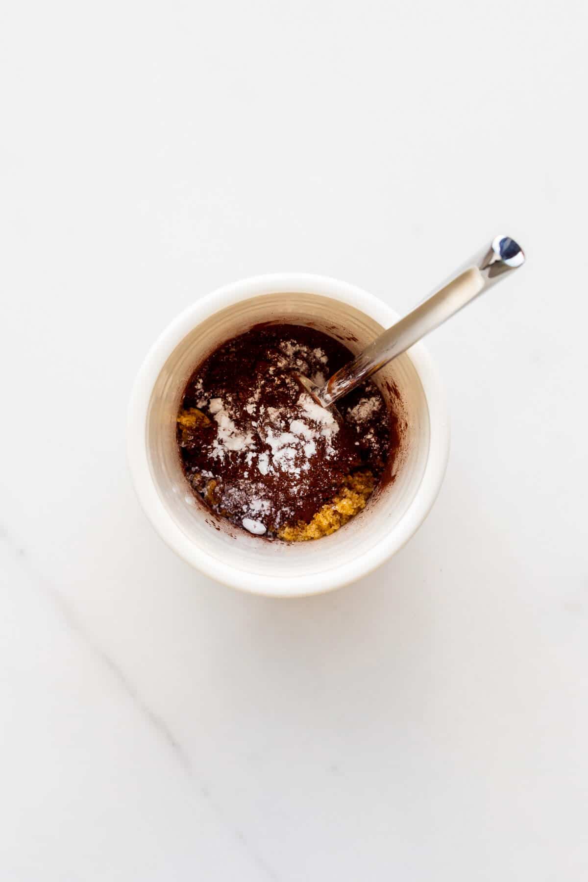 Mixing ingredients for a chocolate cake in a mug with a fork.