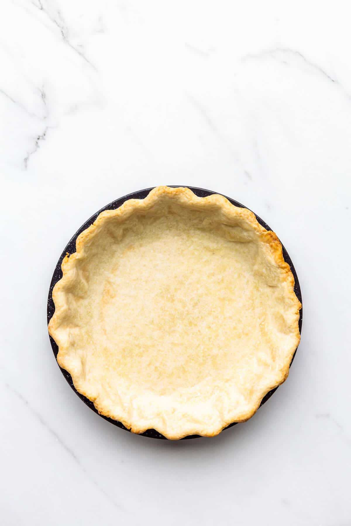 Par-baked pie crust ready to be filled with a pumpkin custard to make pumpkin pie.