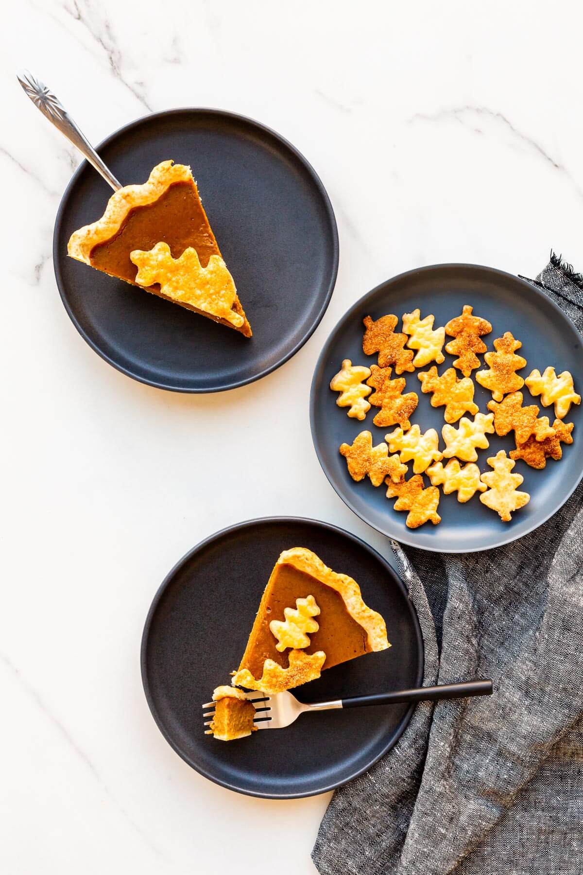 Slices of pumpkin pie served on black plates.