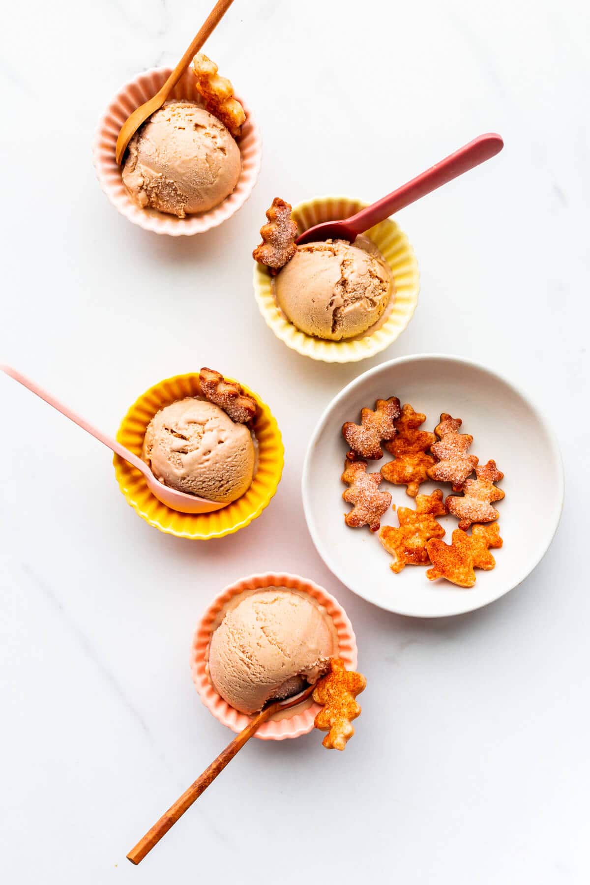 Scoops of pumpkin ice cream in little bowls with pie crust cookies.