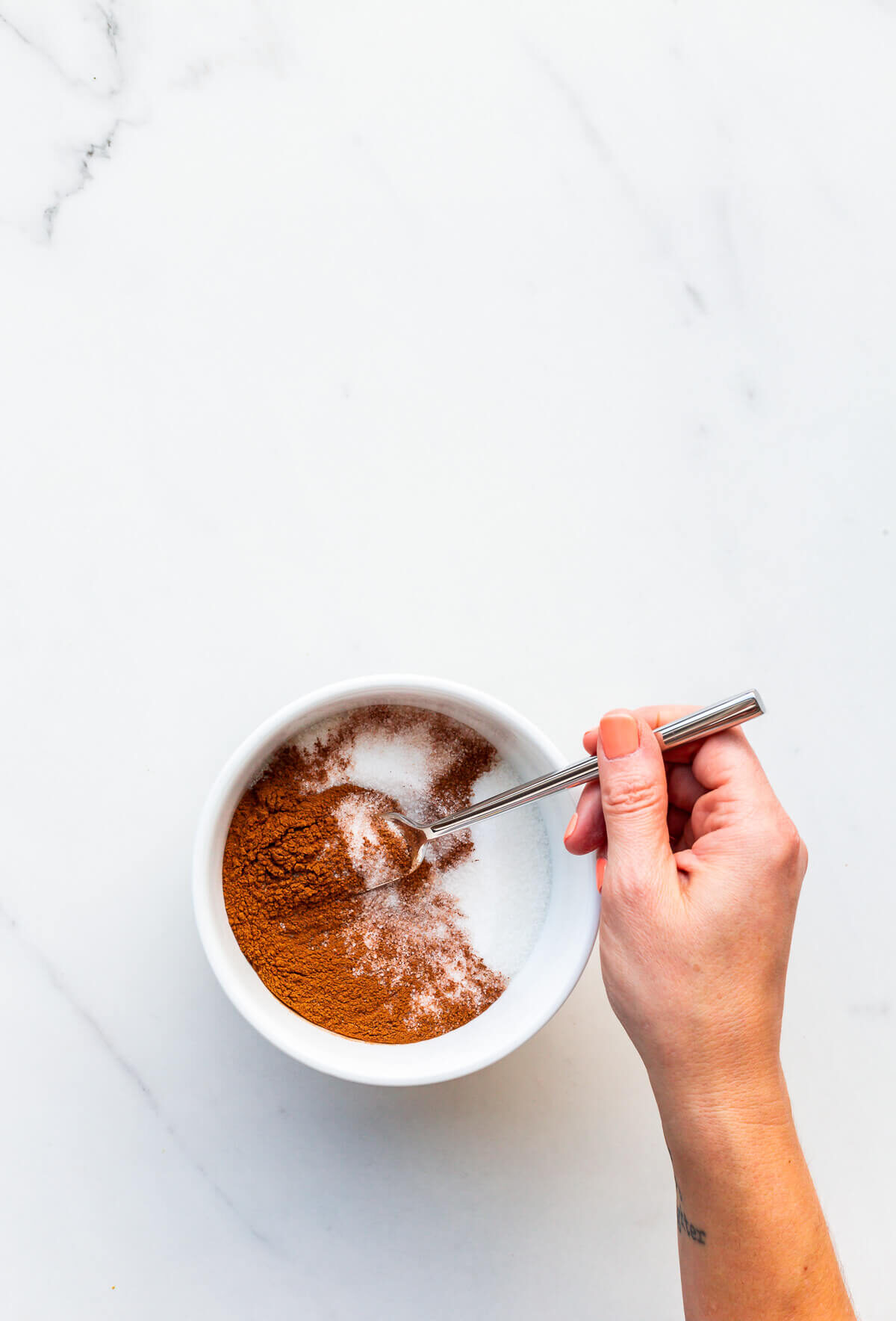 Mixing cinnamon and sugar with a fork to make cinnamon sugar.