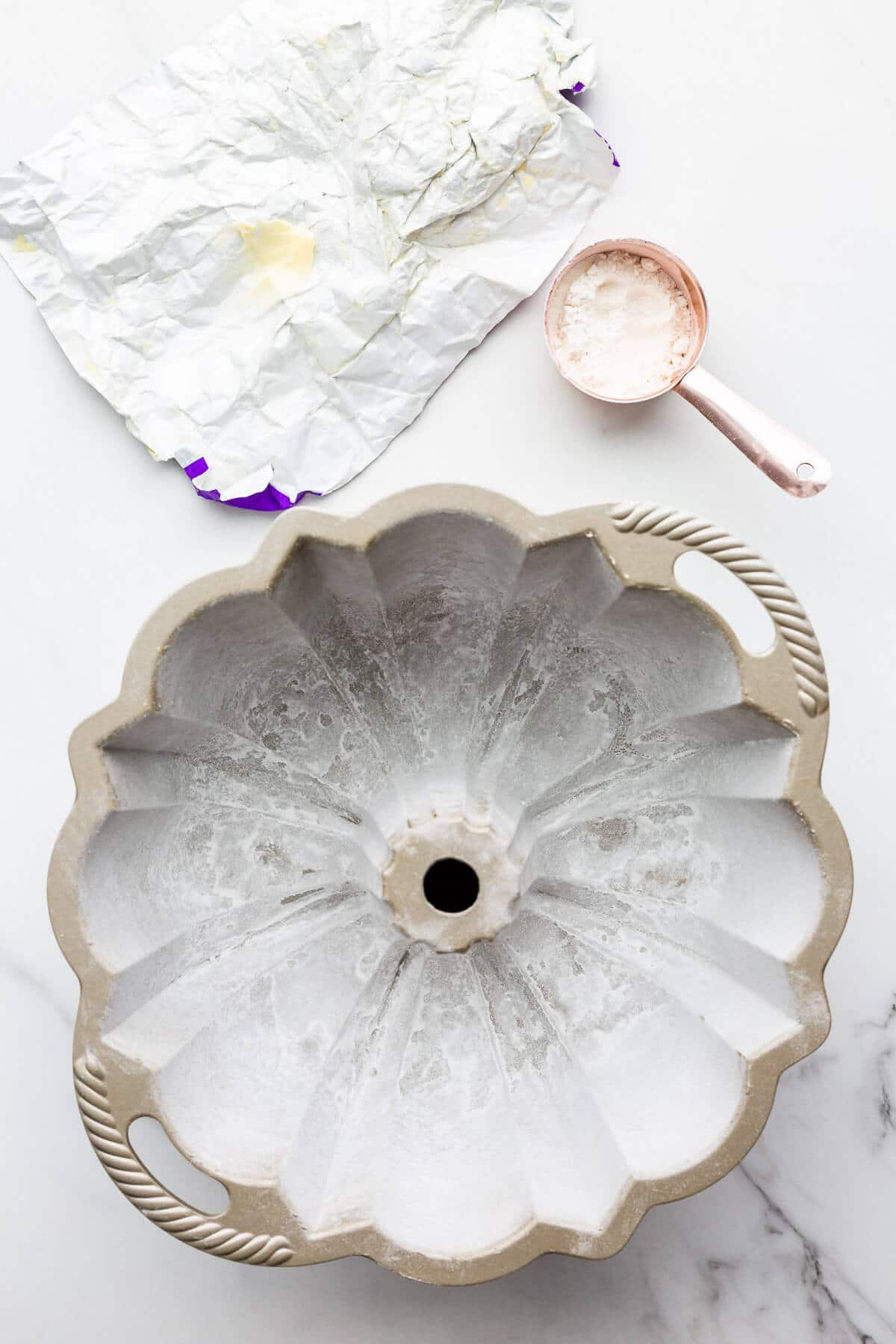 Greasing and flouring a bundt pan so that the cake doesn't stick.